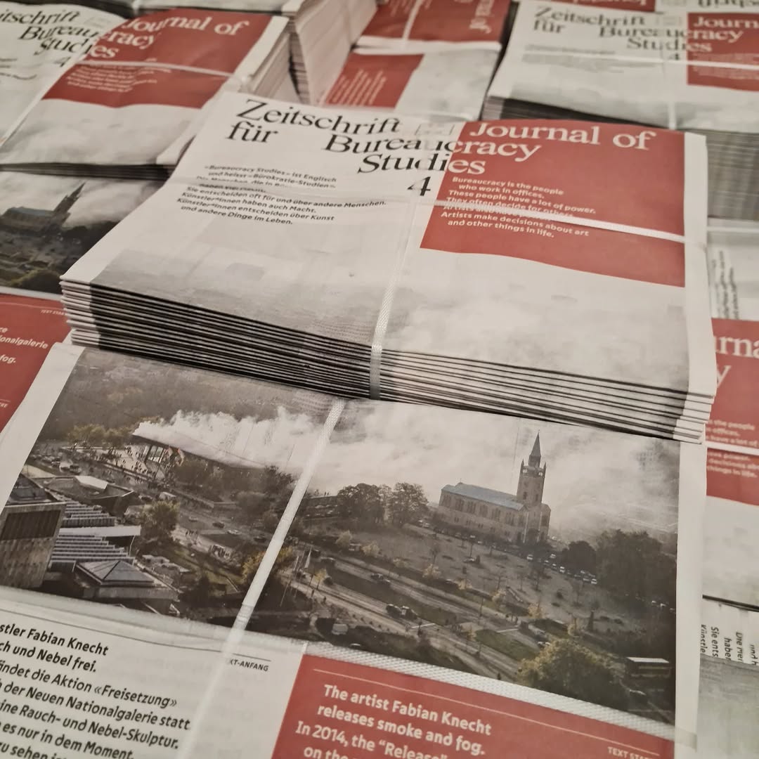 Ausgaben der Ausgbe 4 der Zeitschrift für Bureaucracy Studies stapeln sich. Die Titel-Seite der Zeitschrift ist weiss und rot mit schwarzem und weissem Text. Das Bild zeigt ein Kunst-Werk von Fabian Knecht.
